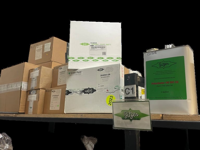 Collection of cardboard boxes and packaging with green logos and labels arranged on a display shelf against a black background